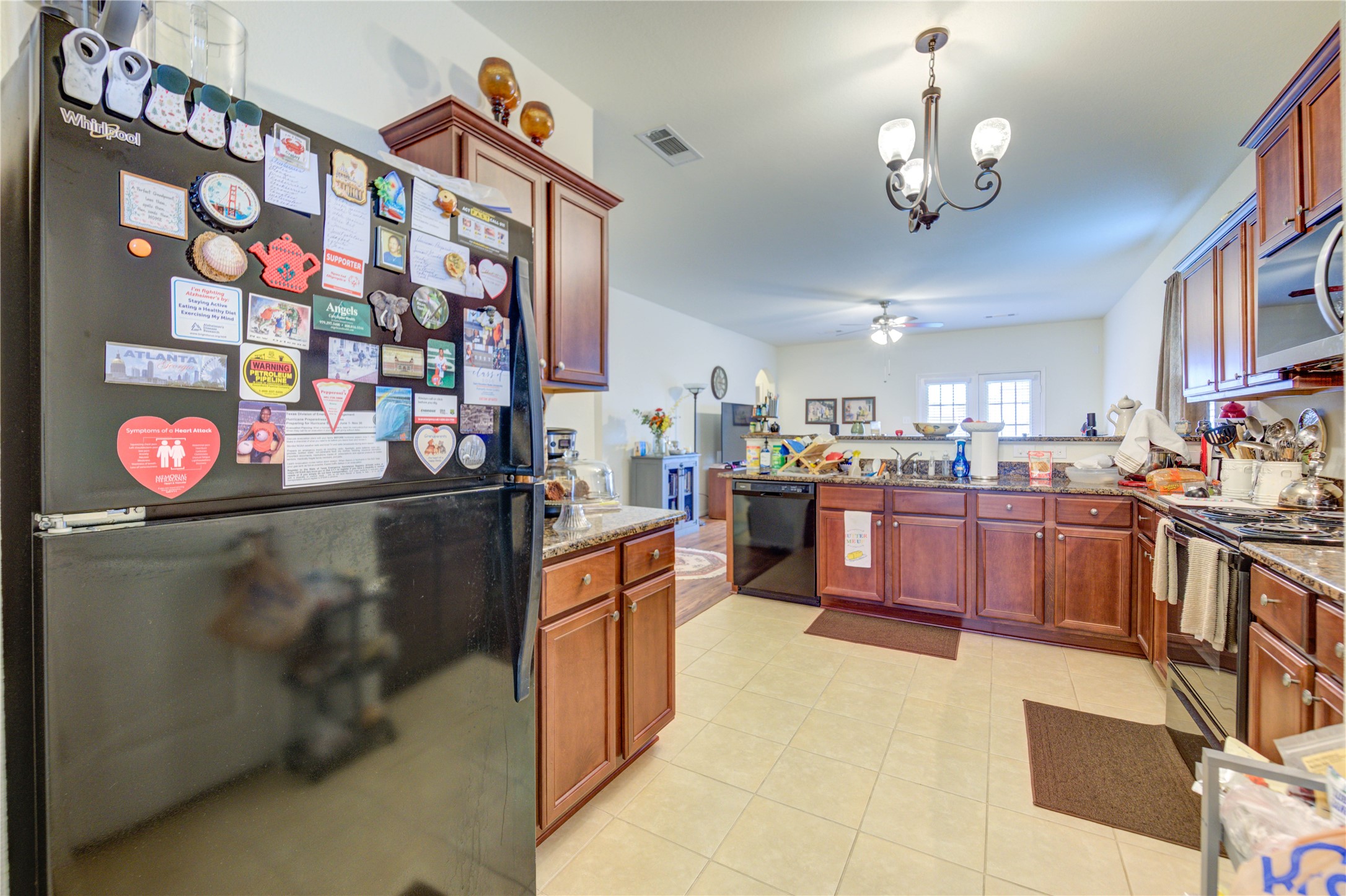 9443 Sky Blue Drive Rosharon, TX 77583 - Photo 8 of 23 Open-concept kitchen with warm wooden cabinets and a granite countertop, leading into a cozy living area.