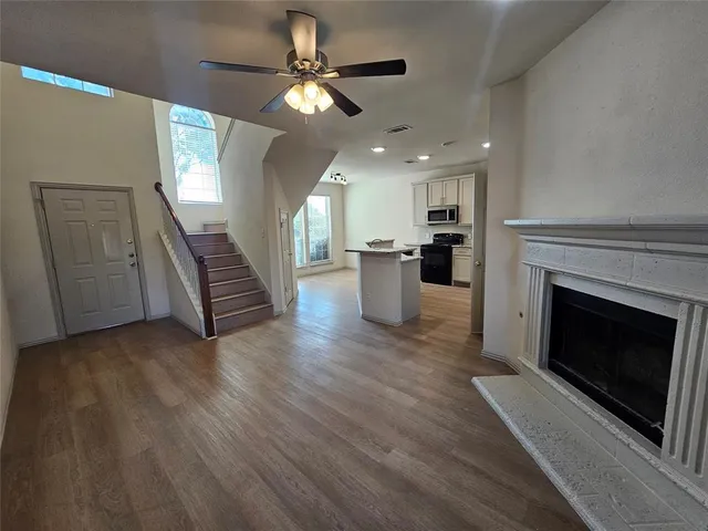 a view of a livingroom with wooden floor fireplace and kitchen space