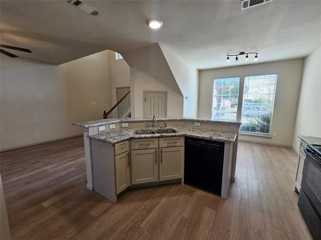 a kitchen with stainless steel appliances granite countertop a stove a sink and a wooden floors