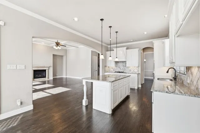 a large kitchen with kitchen island a stove a sink a center island and wooden floor