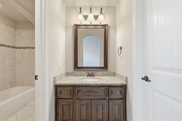 a bathroom with a granite countertop sink a mirror and a bathtub