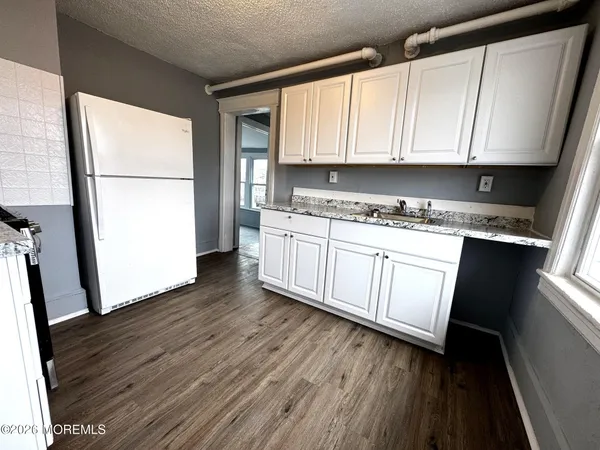 a kitchen with stainless steel appliances granite countertop a refrigerator a sink dishwasher a stove and white countertops with wooden floor