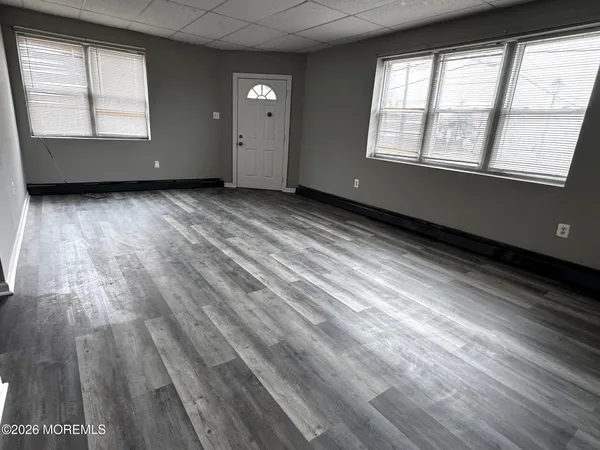 an empty room with wooden floor and windows
