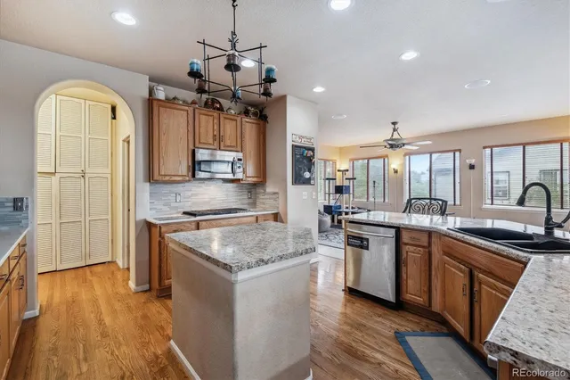 a kitchen with stainless steel appliances granite countertop a sink a stove and a wooden floors