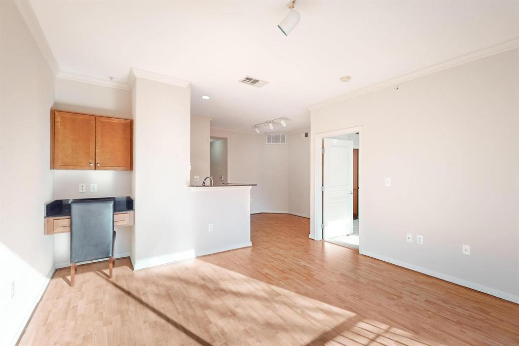 Unfurnished living room with crown molding, light wood finished floors, rail lighting, and a desk