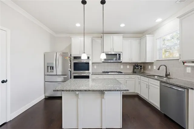 a kitchen with stainless steel appliances granite countertop a sink a stove a refrigerator a microwave and cabinets