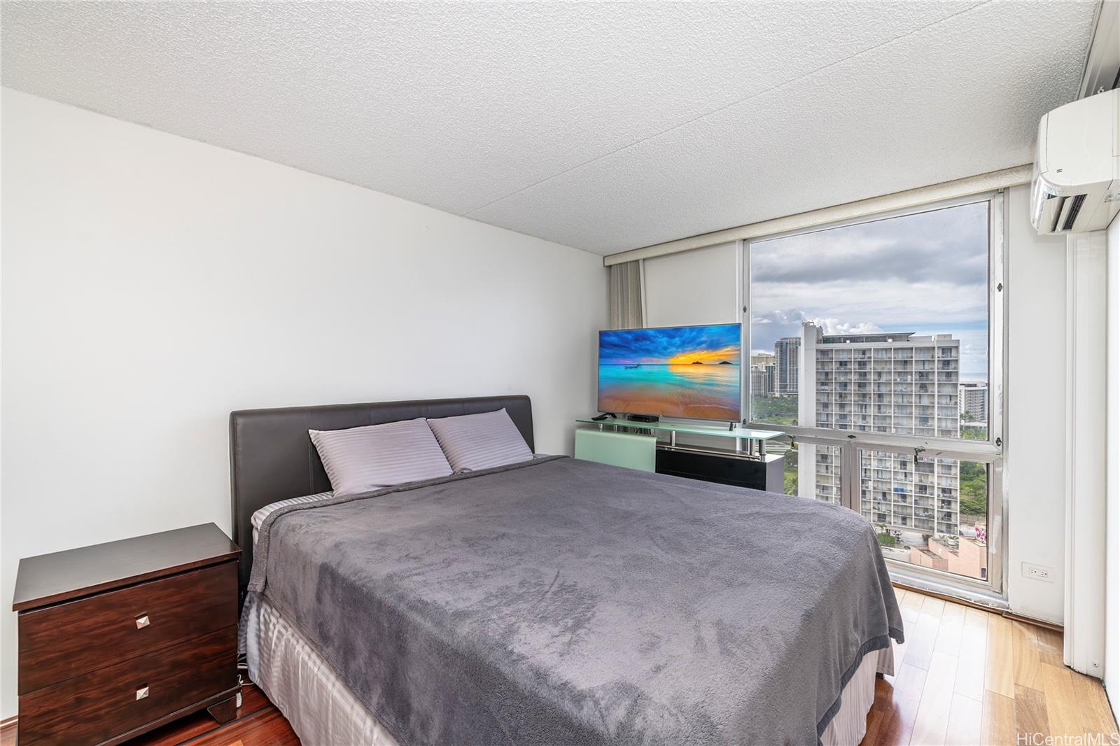469 Ena Road, Unit 2205 Honolulu, HI 96815 - Photo 5 of 21 a bedroom with a bed a dresser and a floor to ceiling window