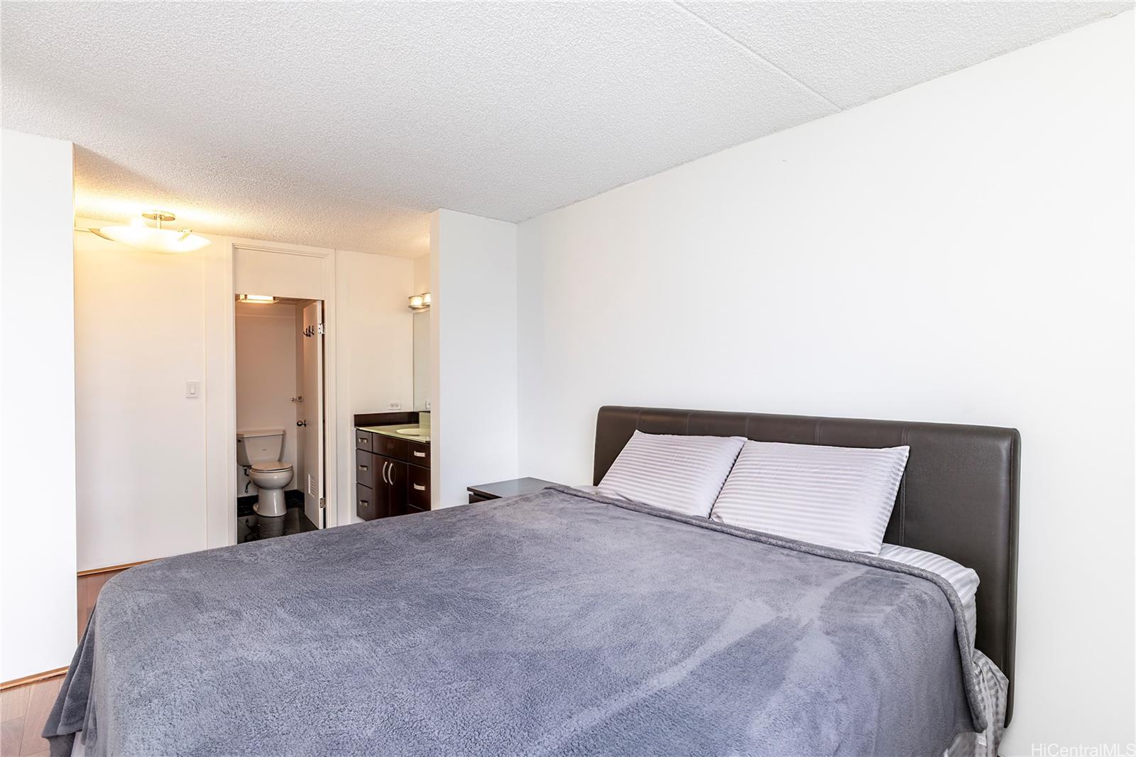 469 Ena Road, Unit 2205 Honolulu, HI 96815 - Photo 6 of 21 a bedroom with a large bed and a chandelier