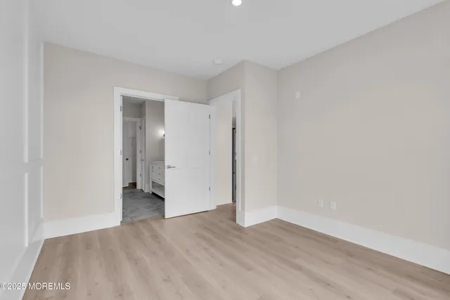 a view of an empty room with wooden floor and closet