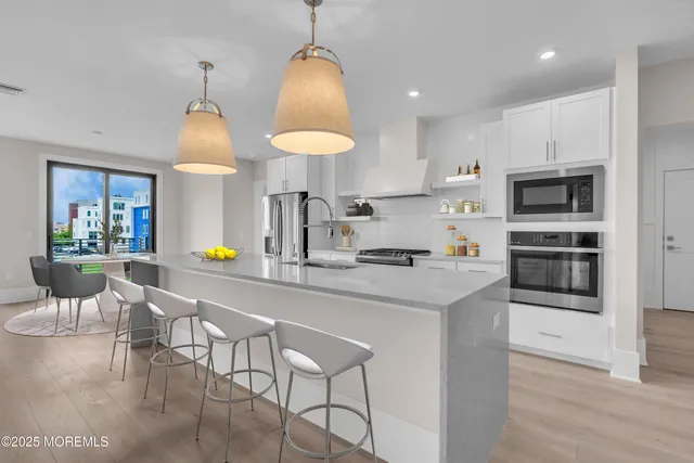 a kitchen with stainless steel appliances granite countertop a sink a stove a refrigerator cabinets and chairs