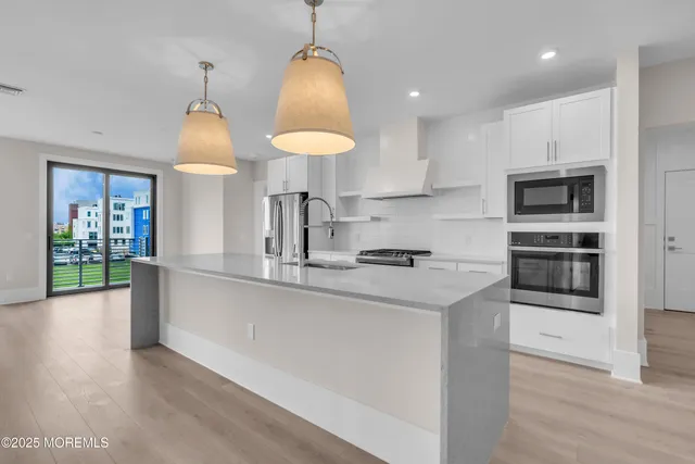 a kitchen with stainless steel appliances granite countertop a sink a stove and a wooden floors