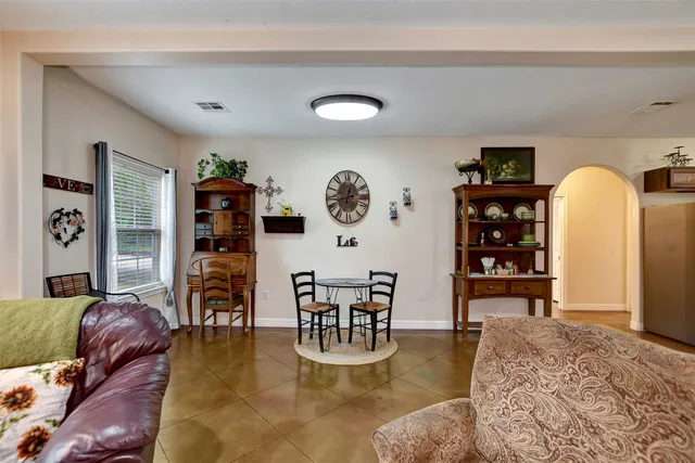 a living room with furniture kitchen view and a wooden floor