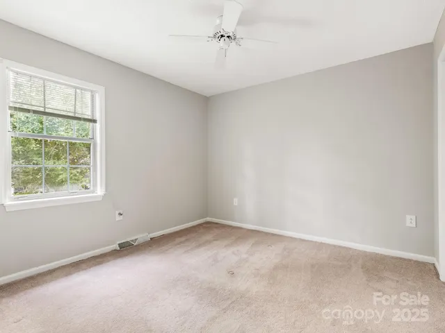 an empty room with windows and ceiling fan