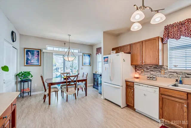 a kitchen with a refrigerator a stove a dining table and chairs with wooden floor