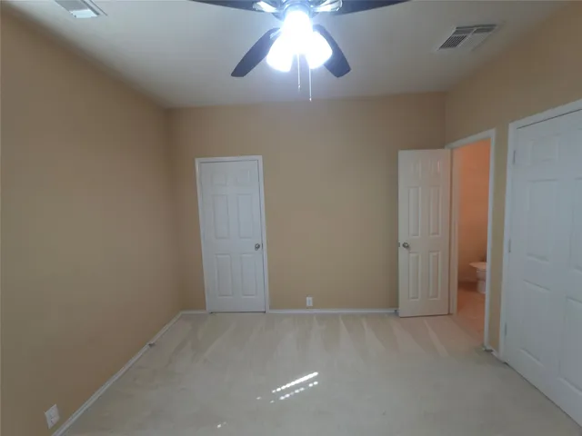 a view of an empty room and chandelier fan