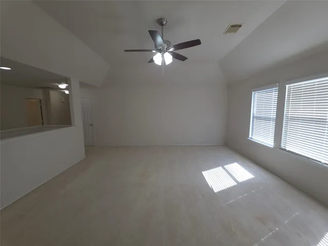 an empty room with windows and fan
