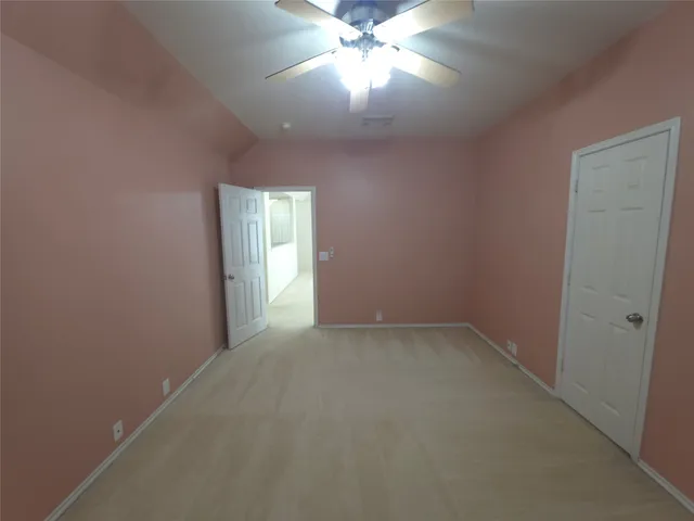 an empty room with a chandelier fan and windows