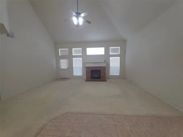 an empty room with a fireplace and chandelier fan
