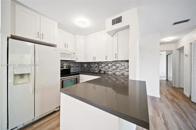 a kitchen with granite countertop white cabinets and stainless steel appliances