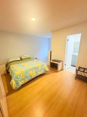 a bedroom with a bed and dresser with wooden floor