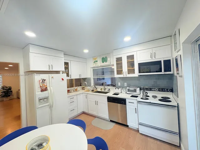 a kitchen with a sink a stove a refrigerator cabinets and a dining table