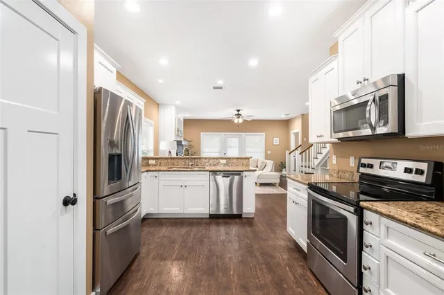 a kitchen with stainless steel appliances granite countertop a refrigerator a stove top oven a sink and dishwasher