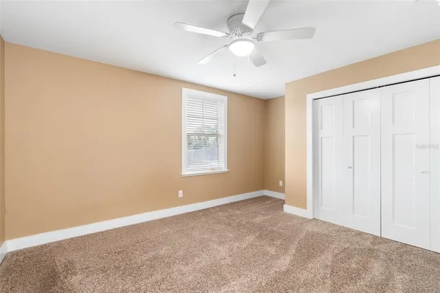 an empty room with windows and fan