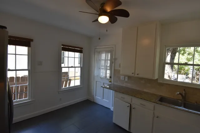a kitchen that has a sink a microwave oven a stove and white cabinets