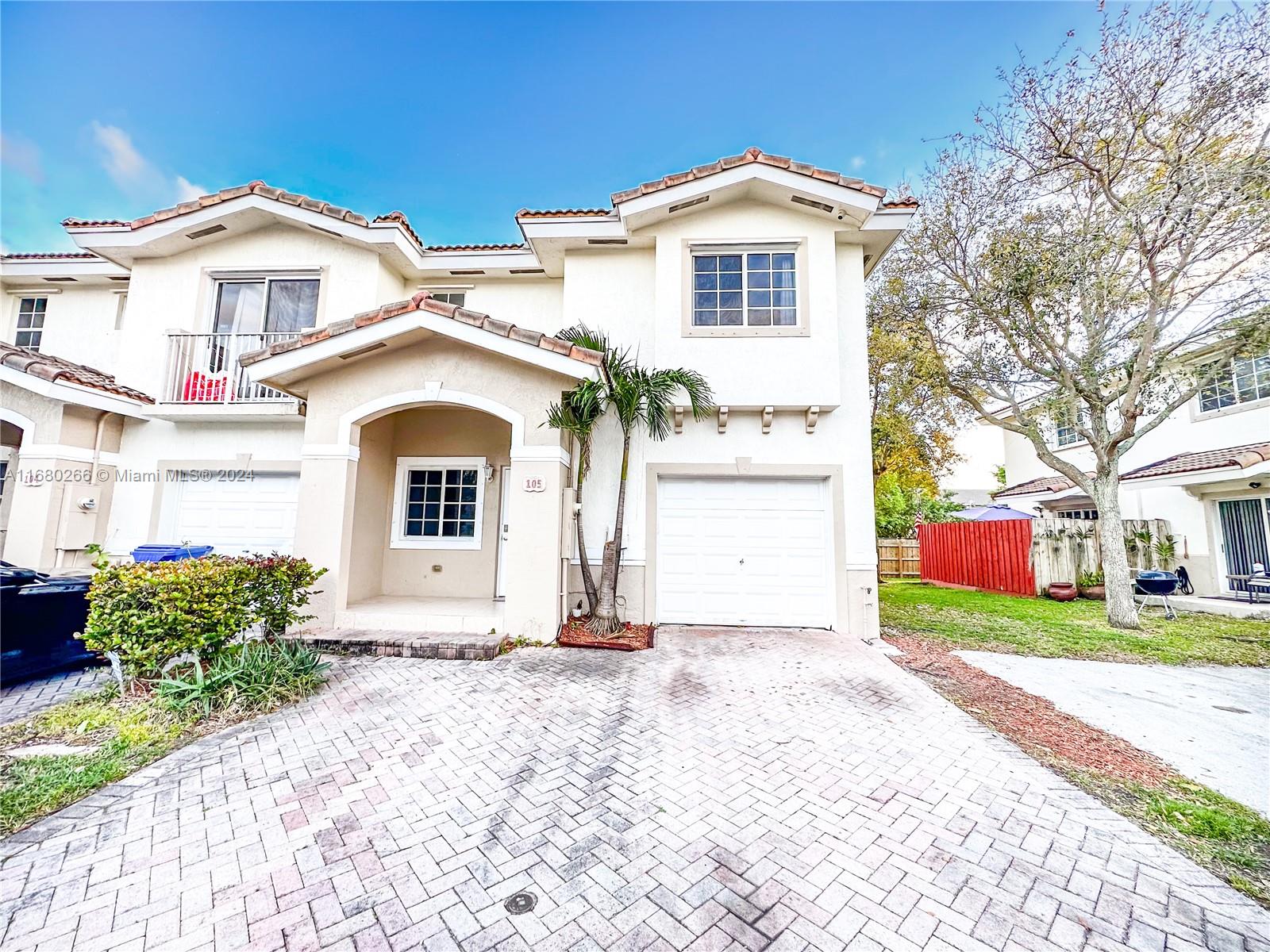 13970 Southwest 260th Street, Unit 105 Homestead, FL 33032 - Photo 1 of 31 a front view of a house with a yard and garage