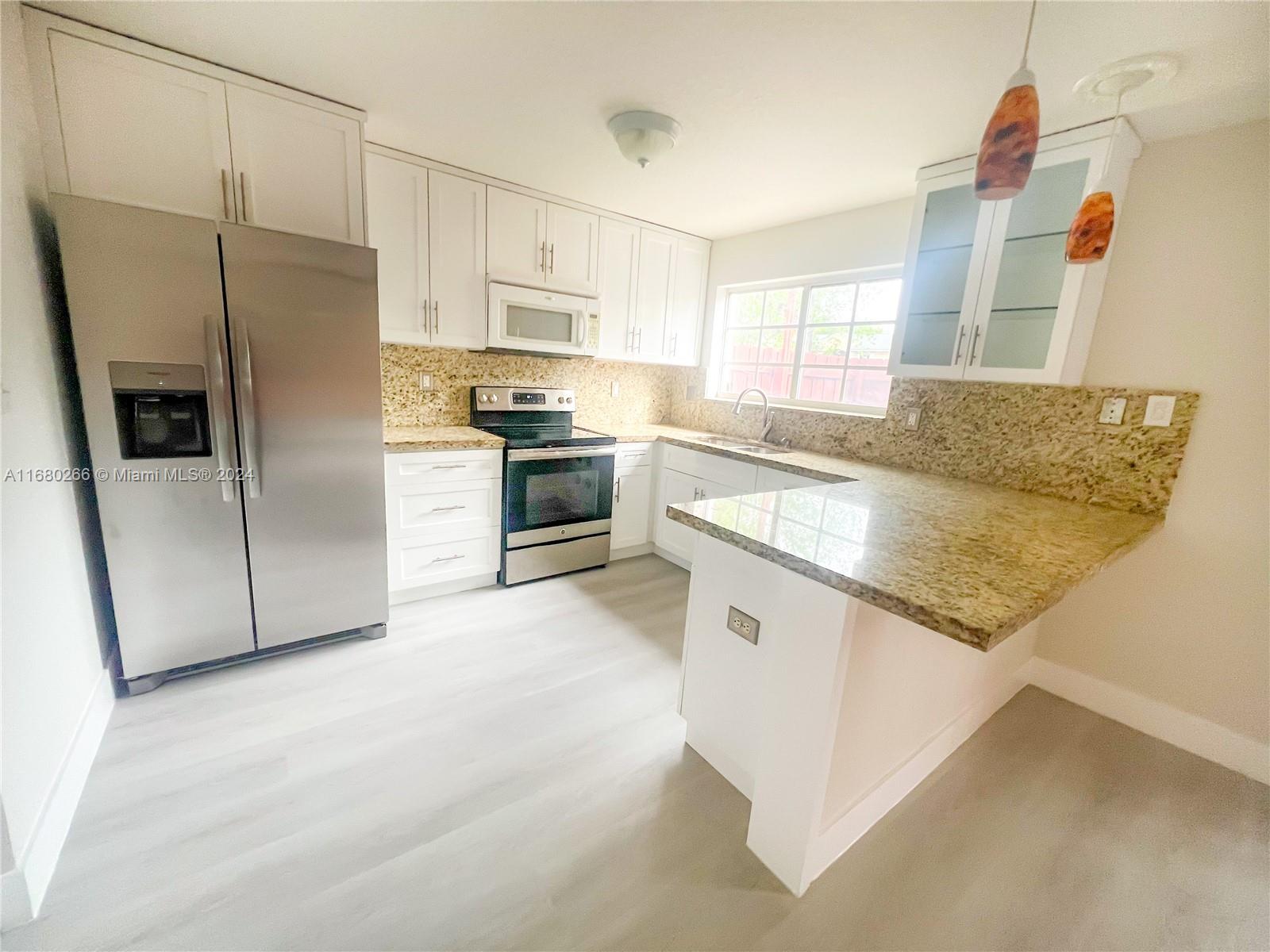 13970 Southwest 260th Street, Unit 105 Homestead, FL 33032 - Photo 11 of 31 a kitchen with stainless steel appliances granite countertop a refrigerator a stove and a sink with cabinets