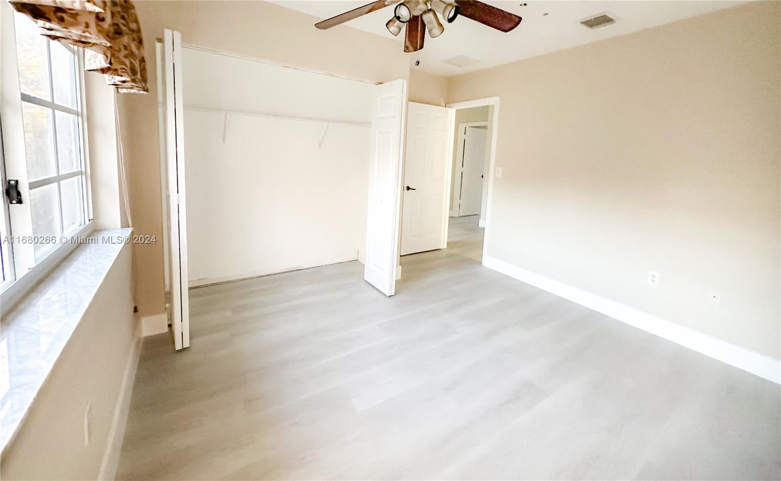 13970 Southwest 260th Street, Unit 105 Homestead, FL 33032 - Photo 19 of 31 an empty room with chandelier fan and windows