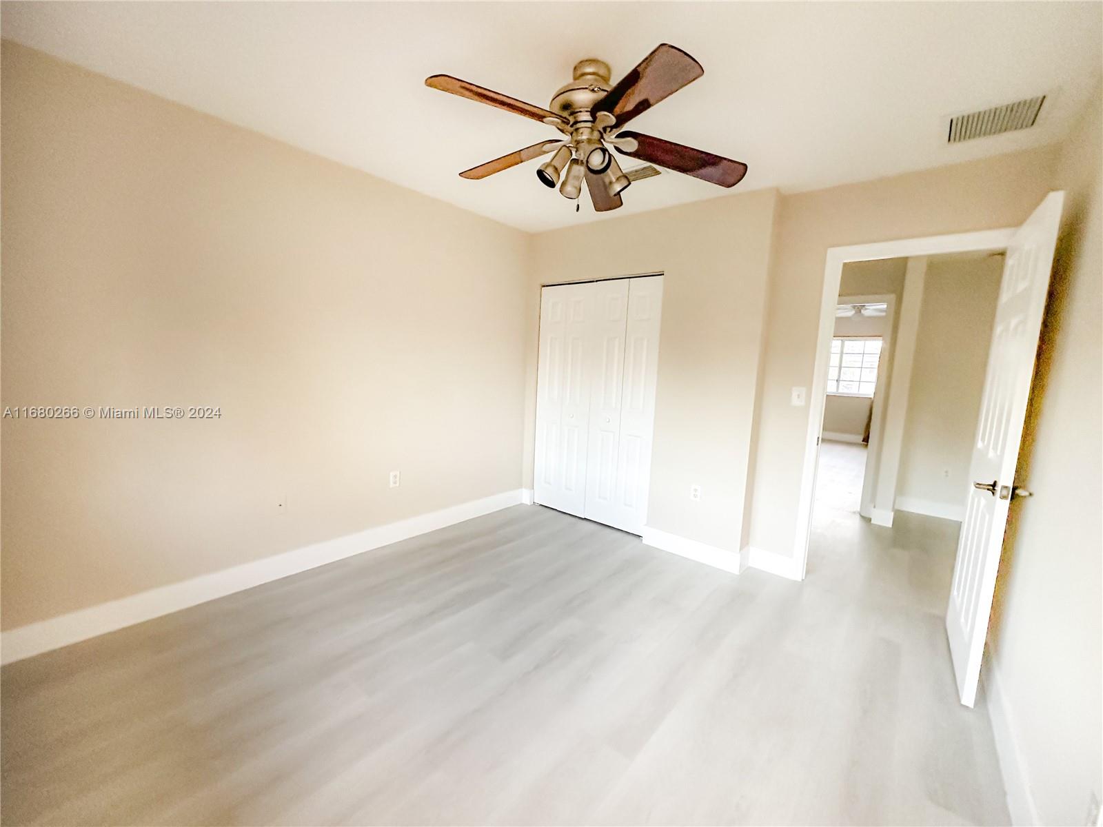 13970 Southwest 260th Street, Unit 105 Homestead, FL 33032 - Photo 21 of 31 an empty room with wooden floor and a ceiling fan