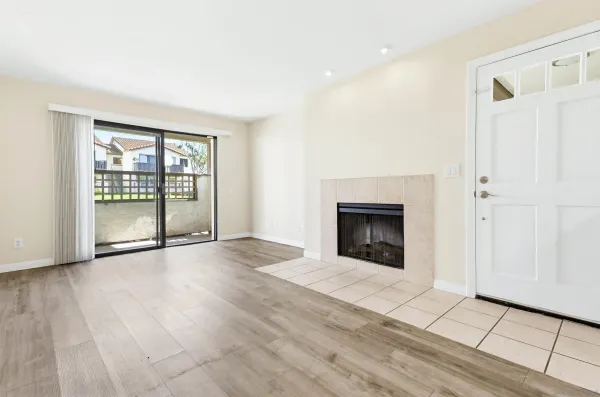 a view of an empty room with glass door and wooden floor
