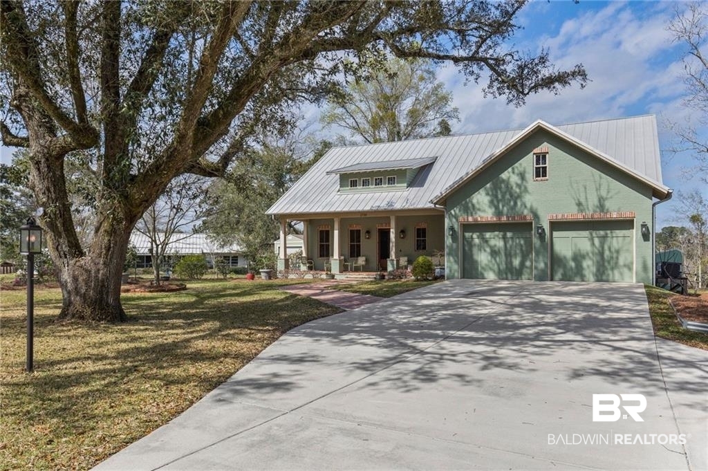 2730 Gator Road Mobile, AL 36605 - Photo 2 of 42 View of front facade featuring covered porch, a front lawn, concrete driveway, a standing seam roof, and a garage