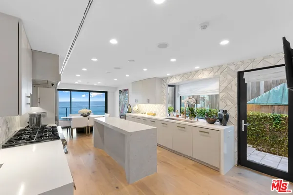 a kitchen with stainless steel appliances a sink a stove a refrigerator cabinets and a large window