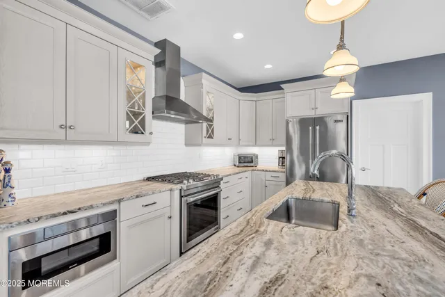 a kitchen with stainless steel appliances granite countertop a sink a stove and a refrigerator