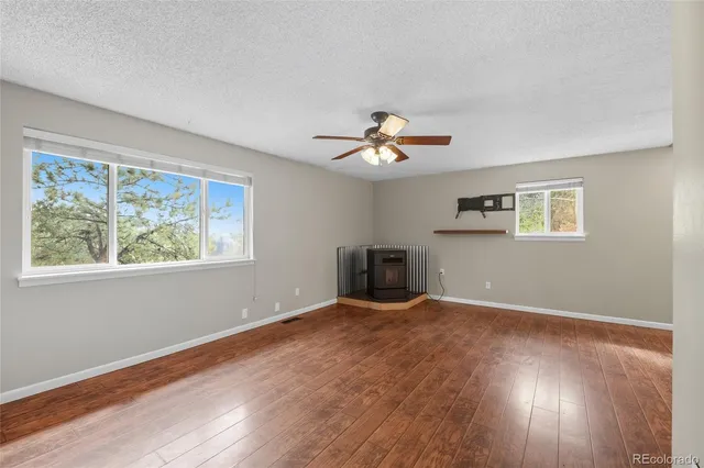 an empty room with wooden floor cabinet and windows