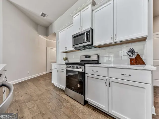 a kitchen with stainless steel appliances granite countertop white cabinets and a granite counter tops