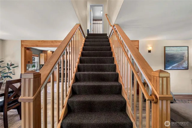 a view of staircase with lots of frames on wall and wooden floor