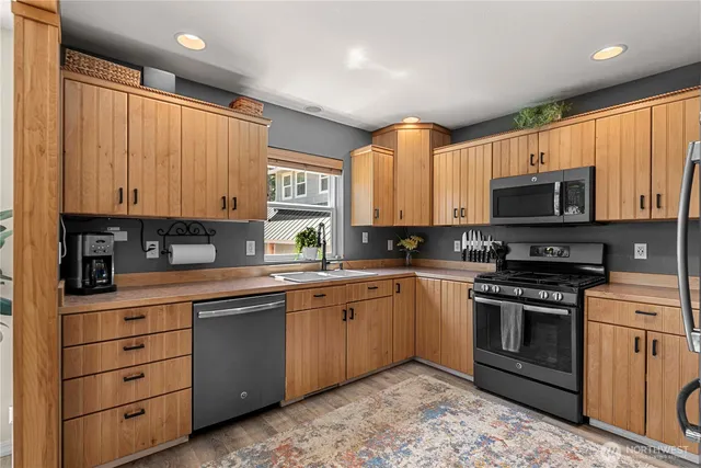 a kitchen with stainless steel appliances granite countertop a stove a sink and a microwave