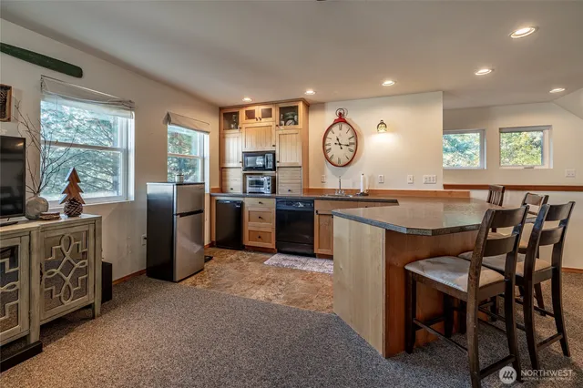 a kitchen with stainless steel appliances granite countertop a stove top oven a sink a dining table and chairs