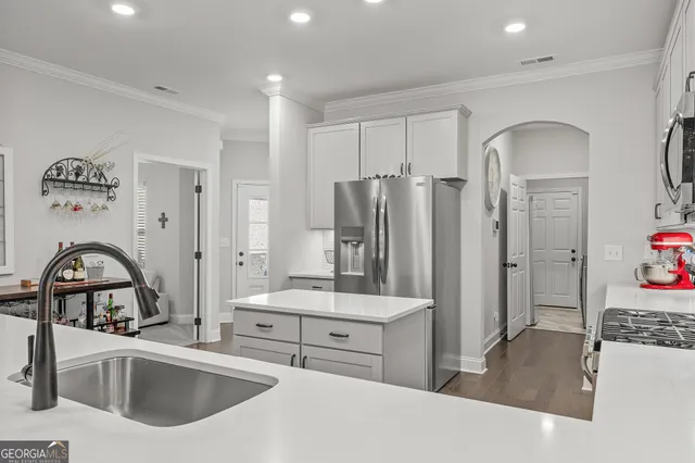 a kitchen with stainless steel appliances granite countertop a refrigerator a sink a stove and a refrigerator with wooden floor