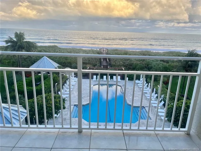 a view of a balcony with chairs and wooden fence