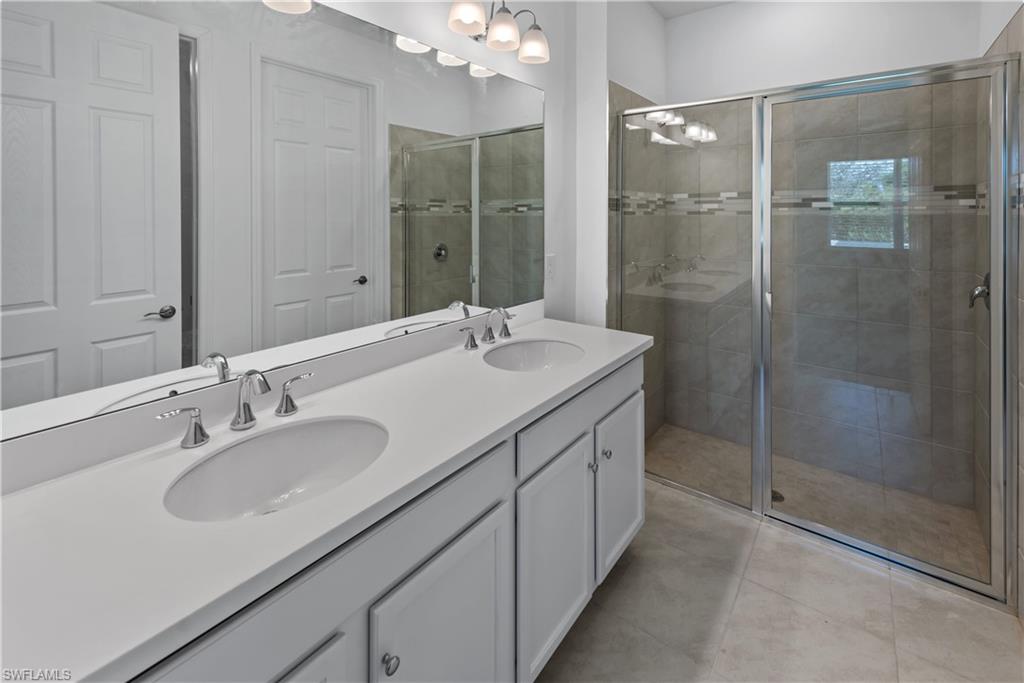 1093 Tranquil Brook Drive Naples, FL 34114 - Photo 11 of 22 a bathroom with a shower sink vanity granite and mirror