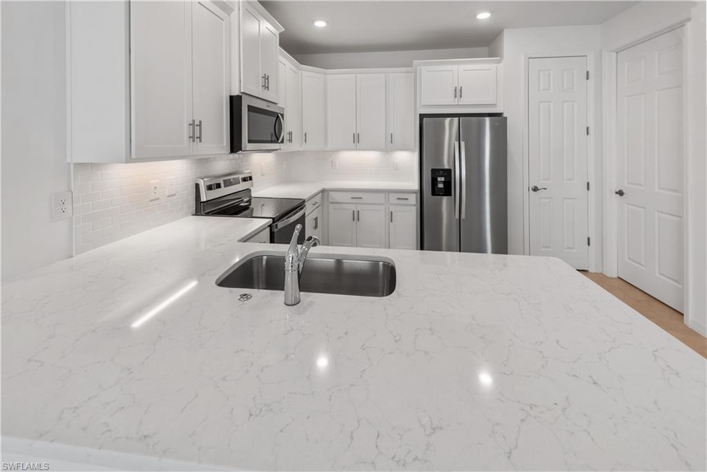 1093 Tranquil Brook Drive Naples, FL 34114 - Photo 6 of 22 a kitchen with stainless steel appliances a refrigerator sink and microwave
