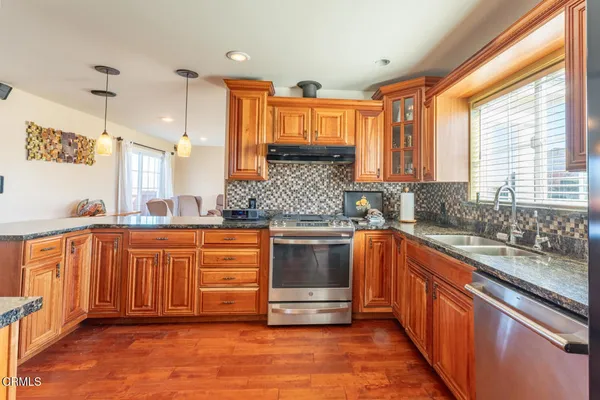 a kitchen with stainless steel appliances granite countertop a stove a sink and a refrigerator
