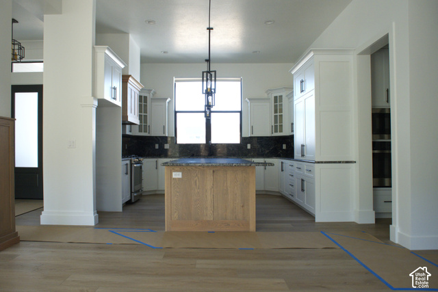 3504 North Sun Dancer Loop Logan, UT 84341 - Photo 5 of 59 Kitchen featuring white shaker cabinetry, dark countertops, a light wood-finish island with a contrasting dark countertop, a window above the sink, and wood-finish flooring