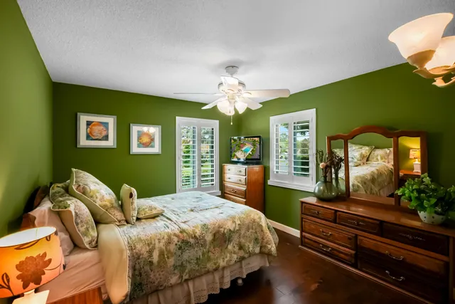 a bedroom with a bed table flowerpot and window