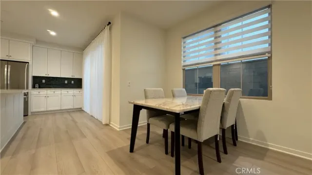 a kitchen with stainless steel appliances kitchen island granite countertop a table chairs sink and cabinets