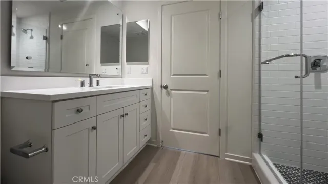 a bathroom with a double vanity sink a mirror and a shower